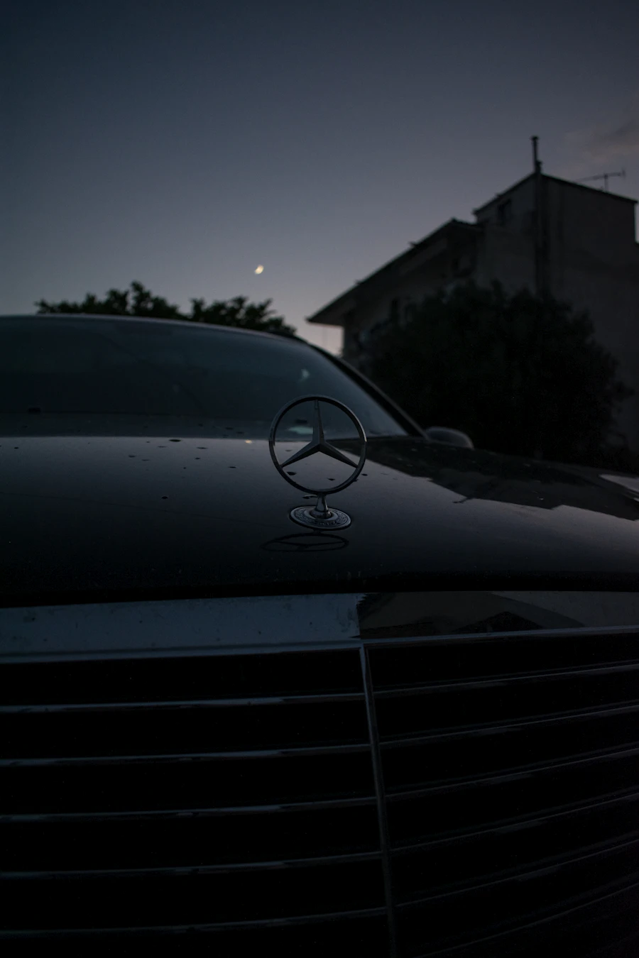 Mercedes-Benz saloon at dusk, three-pointed star on the bonnet