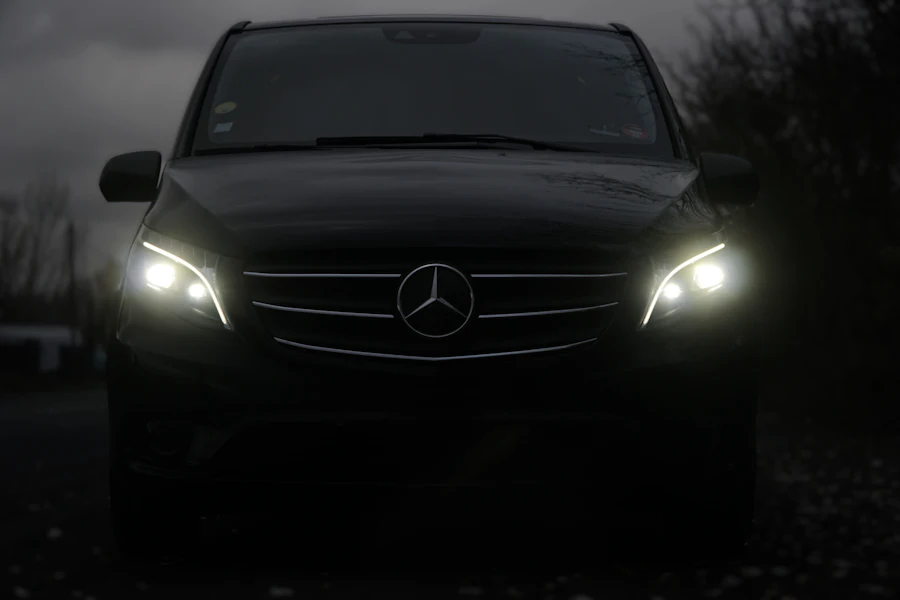 Dark Mercedes-Benz V-Class people carrier with headlights lit at dusk