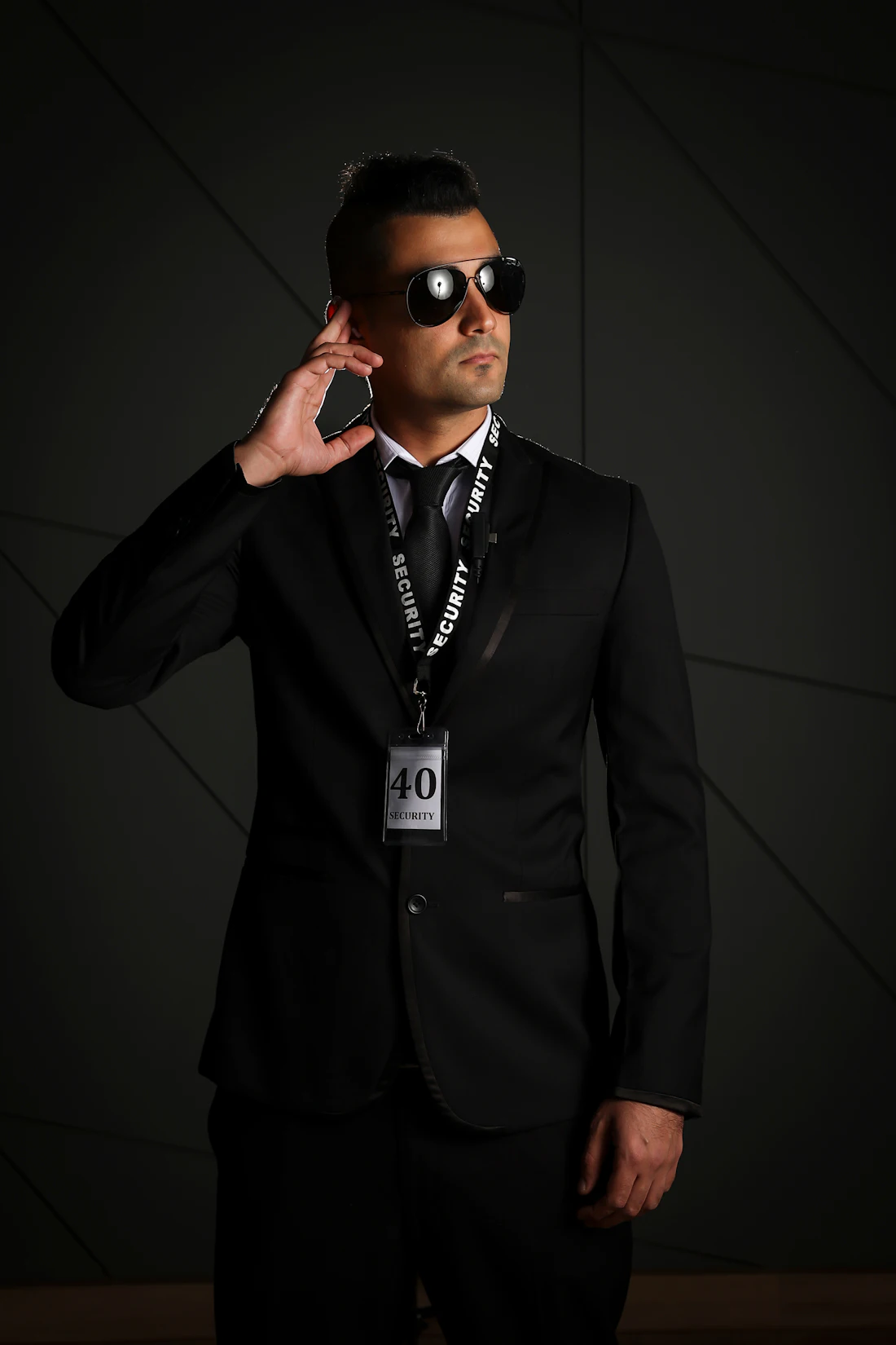 Close protection officer in a dark suit, earpiece in, standing watch
